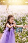 Чарівна азіатська дитина в сукні ловить мильні бульбашки на квітковому полі — стокове фото