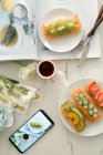 Blick auf leckeres gesundes Frühstück und Smartphone auf weißem Tisch — Stockfoto