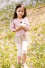 Adorable asian kid holding cute rabbit outdoors — Stock Photo