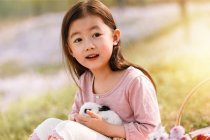 Adorable asiático niño holding lindo conejo al aire libre - foto de stock