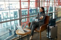 Красива молода бізнес-леді використовує ноутбук і смартфон в залі аеропорту — стокове фото