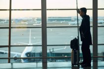 Вид збоку молодого бізнесмена з багажем в аеропорту — стокове фото