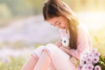 Adorable asian kid holding cute rabbit outdoors — Stock Photo