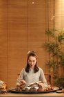 Hermosa mujer china joven en ropa tradicional haciendo té de hierbas - foto de stock