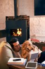 Bonito ásia homem leitura livro enquanto descansando com cão no casa — Fotografia de Stock