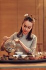 Красивая концентрированная молодая китаянка наливает чай — стоковое фото