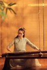Зосереджена молода азіатська жінка грає традиційний китайський інструмент Гуджен — стокове фото