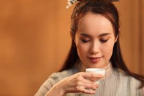 Vue rapprochée de la jeune femme asiatique tenant tasse de thé — Photo de stock