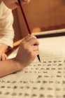 Ritagliato colpo di donna in possesso di pennello calligrafia e scrittura caratteri cinesi — Foto stock