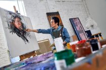 Focused young male artist painting picture in art studio — Stock Photo