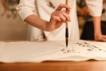 Close-up partial view of woman holding calligraphy brush and writing chinese characters — Stock Photo