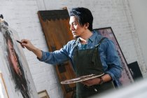 Seitenansicht eines konzentrierten männlichen Künstlers, der Porträt im Atelier malt — Stockfoto