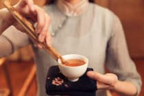 Cropped shot of young woman holding white cup with hot organic herbal tea — Stock Photo