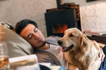 Handsome asian man hugging dog and sleeping at home — Stock Photo