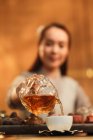 Close-up view of young asian woman pouring tea into cup, selective focus — Stock Photo
