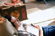 Vue grand angle de barbu asiatique homme couché sur haricot sac chaise avec livre — Photo de stock