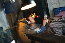 Вид на молоду людину в навушниках Холдинг вініловий рекорд і прослуховування музики в домашніх умовах — стокове фото