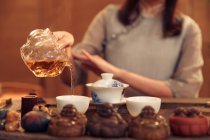 Primo piano vista parziale della donna versando il tè in tazze bianche — Foto stock
