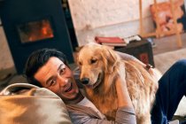 Happy asian man hugging dog and smiling at camera at home — Stock Photo