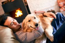 Feliz jovem asiático homem relaxante com cão em casa — Fotografia de Stock