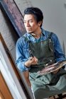 Задумчивый китайский художник держит палитру и кисть — стоковое фото