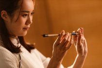 Close-up view of beautiful young chinese woman holding calligraphy brush — Stock Photo