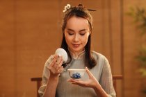 Schöne lächelnde junge Chinesin mit Tasse und duftendem aromatischen Tee — Stockfoto