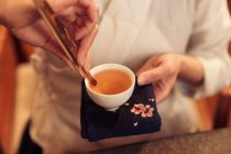 Tiro recortado de mujer sosteniendo taza blanca con té de hierbas aromáticas calientes - foto de stock