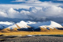 Increíble paisaje con montañas cubiertas de nieve y valle bajo el cielo nublado, el Tíbet - foto de stock