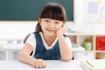Retrato de uma menina sentada na sala de aula — Fotografia de Stock