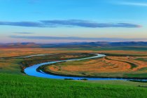 Beautiful landscape with green grass, river, hills and blue sky — Stock Photo
