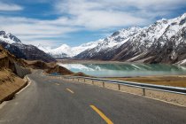 Estrada vazia, montanhas cobertas de neve e belo lago no Tibete — Fotografia de Stock