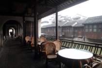 Mesas con sillas en la terraza, canal y casas en Huzhou, Zhejiang, China - foto de stock