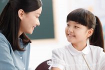 Female teacher helping student studying in classroom — Stock Photo