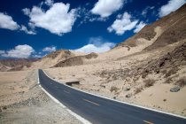 Camino de asfalto vacío en el valle de la montaña en el día soleado, Tíbet - foto de stock