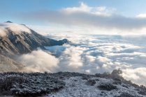 Paisaje de montaña con montañas cubiertas de nieve en las nubes - foto de stock