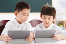 Dos estudiantes usando tableta digital en el aula - foto de stock