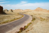 Estrada de asfalto no deserto com montanhas rochosas cênicas no dia ensolarado — Fotografia de Stock