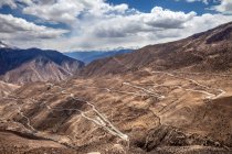 Вид с воздуха на Сычуань-Тибетское шоссе в живописных горах и облачное небо — стоковое фото