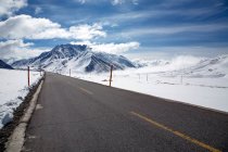 Empty asphalt road and beautiful snow-covered mountains in Tibet — Stock Photo