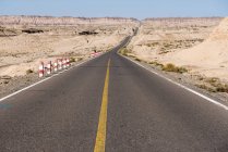 Асфальтовая дорога в пустыне с живописными скалистыми горами в солнечный день — стоковое фото