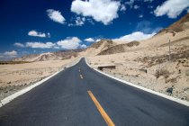 Route asphaltée vide dans la vallée de montagne au jour ensoleillé, Tibet — Photo de stock