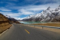 Пустая дорога, заснеженные горы и красивое озеро в Тибете — стоковое фото