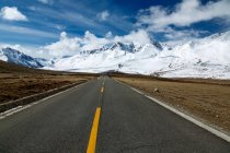 Estrada de asfalto vazia e belas montanhas cobertas de neve no Tibete — Fotografia de Stock