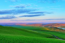 Paysage étonnant avec collines herbeuses et rivière dans la vallée pendant le coucher du soleil — Photo de stock