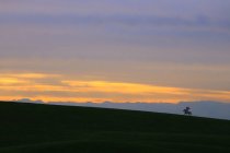 Bellissimo paesaggio con alba su prati e sagome di montagne — Foto stock