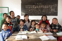 Rural female teacher and happy chinese pupils in classroom — Stock Photo