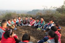 Alunos chineses rurais sentados no chão e brincando ao ar livre — Fotografia de Stock