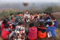 Junge Lehrerin aus dem ländlichen Raum liest Schülern im Freien ein Buch vor — Stockfoto
