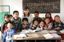 Chinesische Landlehrerin und Schüler lächeln im Klassenzimmer in die Kamera — Stockfoto